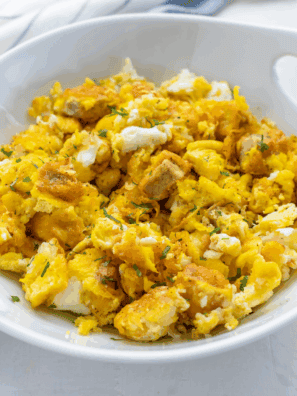 Air fryer breakfast bowl with scrambled eggs, sausage, crispy hash browns, and melted cheese served in a white bowl.