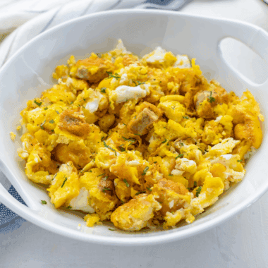 Air fryer breakfast bowl with scrambled eggs, sausage, crispy hash browns, and melted cheese served in a white bowl.