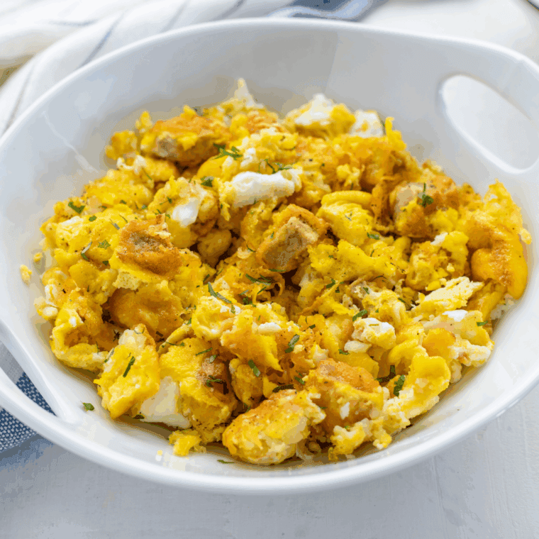 Air fryer breakfast bowl with scrambled eggs, sausage, crispy hash browns, and melted cheese served in a white bowl.