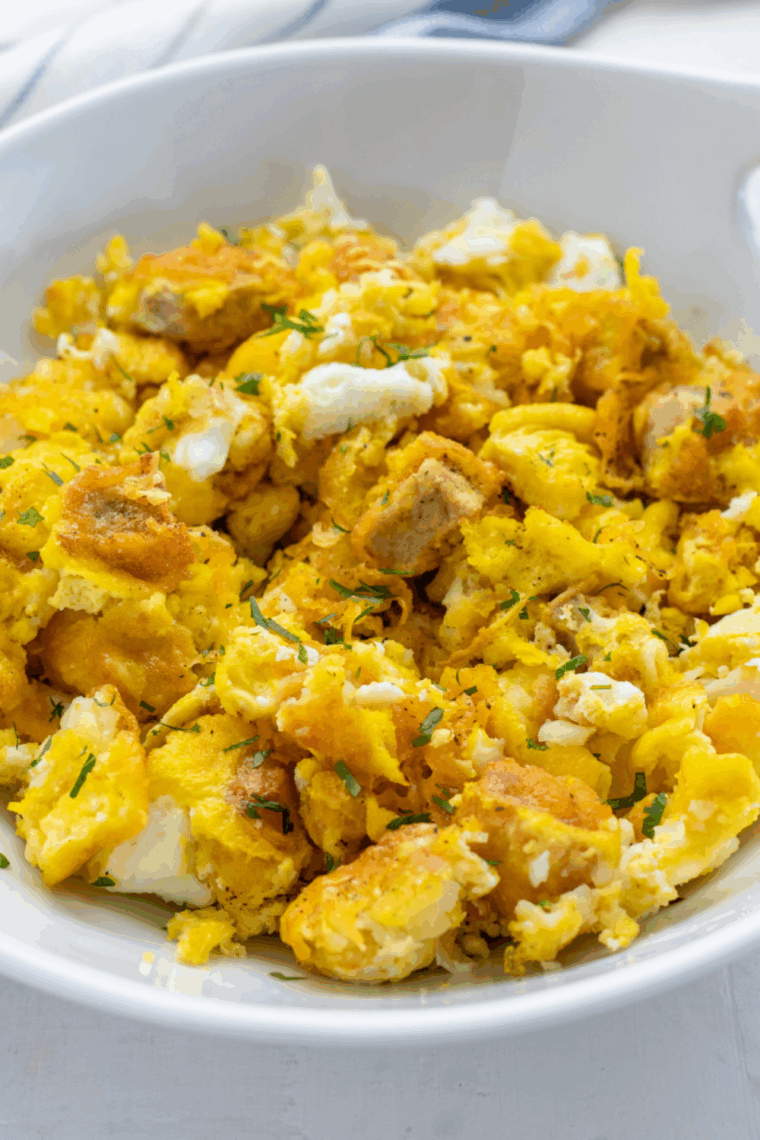 Close-up of a Bob Evans-style breakfast bowl with scrambled eggs, sausage, melted cheddar cheese, and crispy hash browns in a white bowl.
