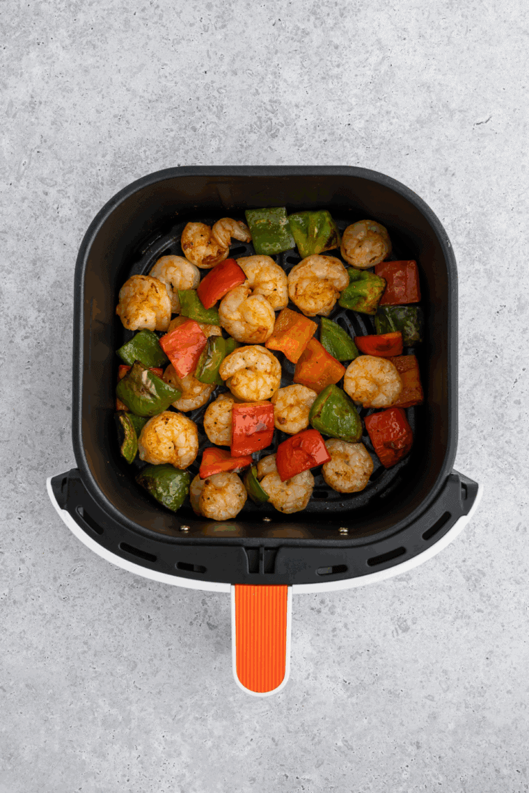 Air Fry the Shrimp and Peppers: Shrimp and bell peppers arranged in a single layer in the air fryer basket, cooking until shrimp are pink and peppers are tender.