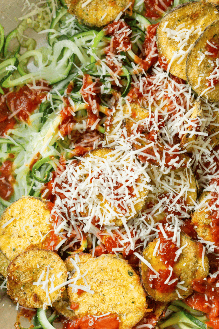 Air fryer basket filled with zucchini noodles tossed in olive oil, seasoned with salt and pepper, ready to cook.
