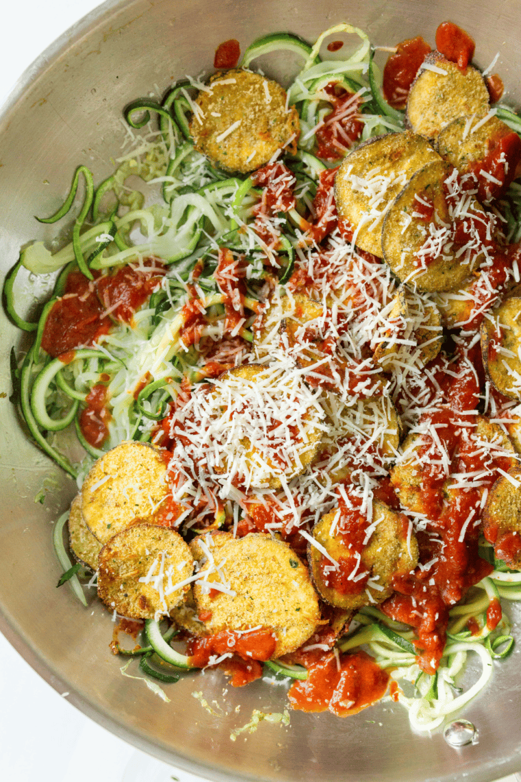 Air fryer zucchini noodles seasoned with olive oil, salt, and pepper, cooked to tender perfection in a basket.