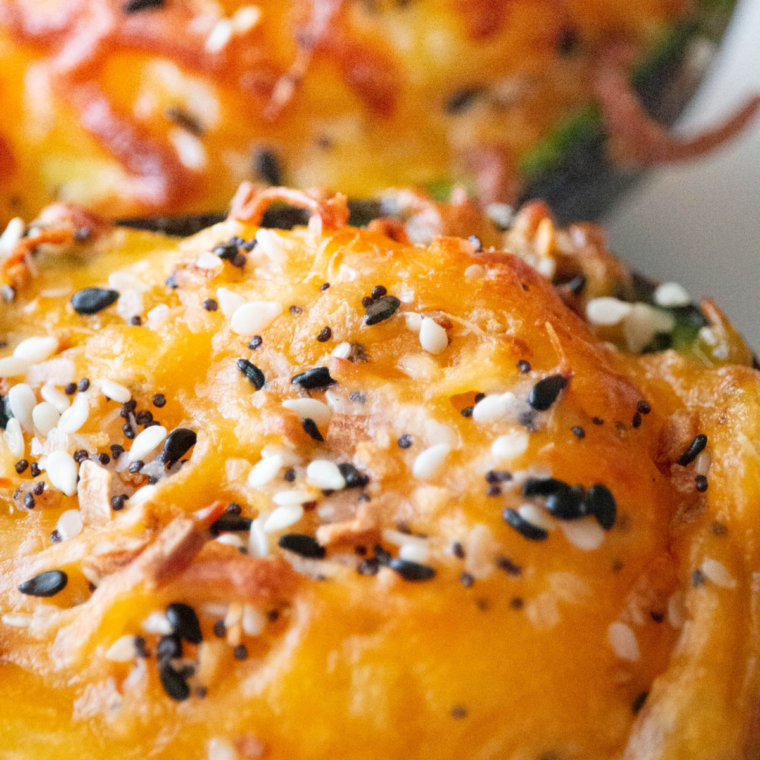 extreme closeup: melted cheese and seasonings on top of an egg in avocado from air fryer