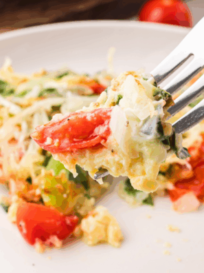 A slice of First Watch Frittata Rustica on a plate, showing eggs, cheese, and mixed vegetables.