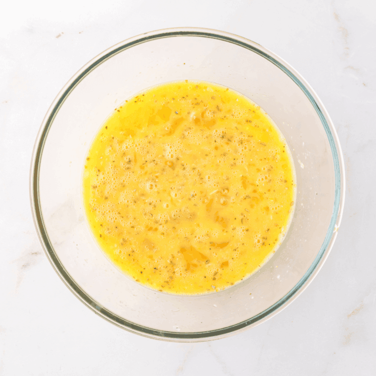 Whisking eggs, milk, Parmesan, garlic powder, oregano, salt, and pepper until smooth.