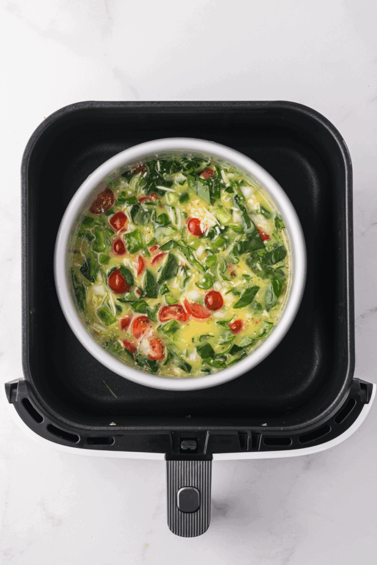 Pouring the egg and vegetable mixture into the pan and placing it in the air fryer.