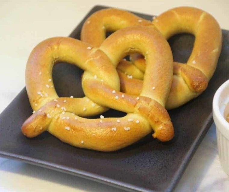 closeup: two cooked frozen pretzels in air fryer stacked on a black plate