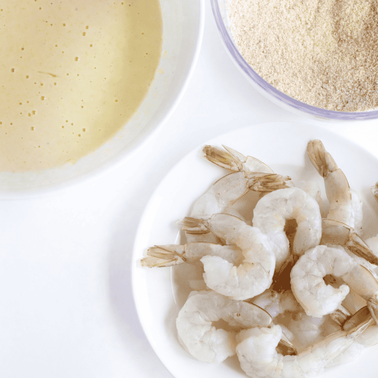 raw shrimp being patted dry and lightly coated in flour before battering&rdquo;