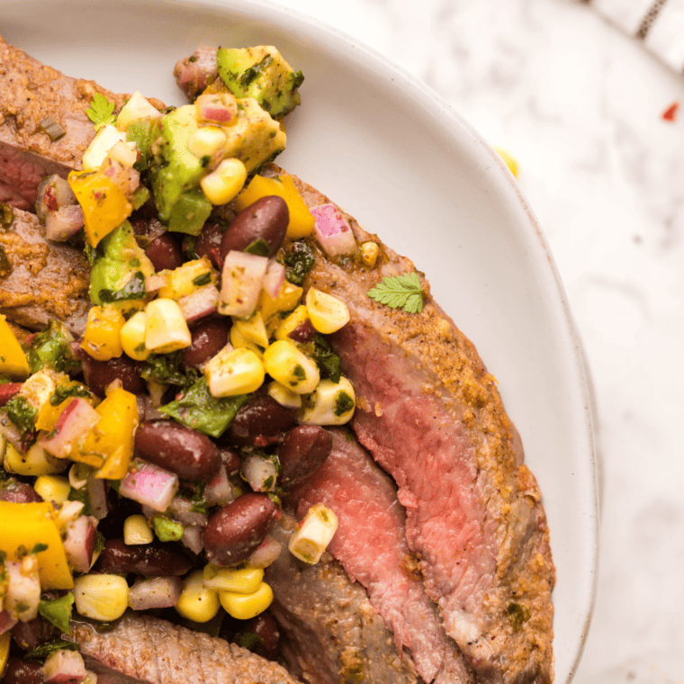 overhead closeup: flank steak made in air fryer on a plate with corn salsa on top