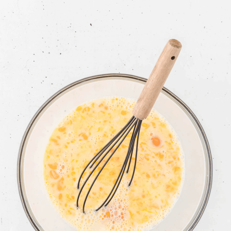 Whisking eggs, milk, salt, and black pepper together in a large mixing bowl for breakfast casserole base.