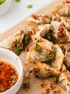 Homemade PF Chang style pork dumplings served on a plate with dipping sauce.
