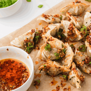 Homemade PF Chang style pork dumplings served on a plate with dipping sauce.