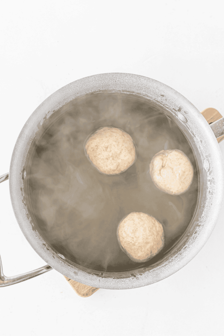 Dipping dough in baking soda water – Dough bites briefly dipped in baking soda water bath for classic pretzel texture.