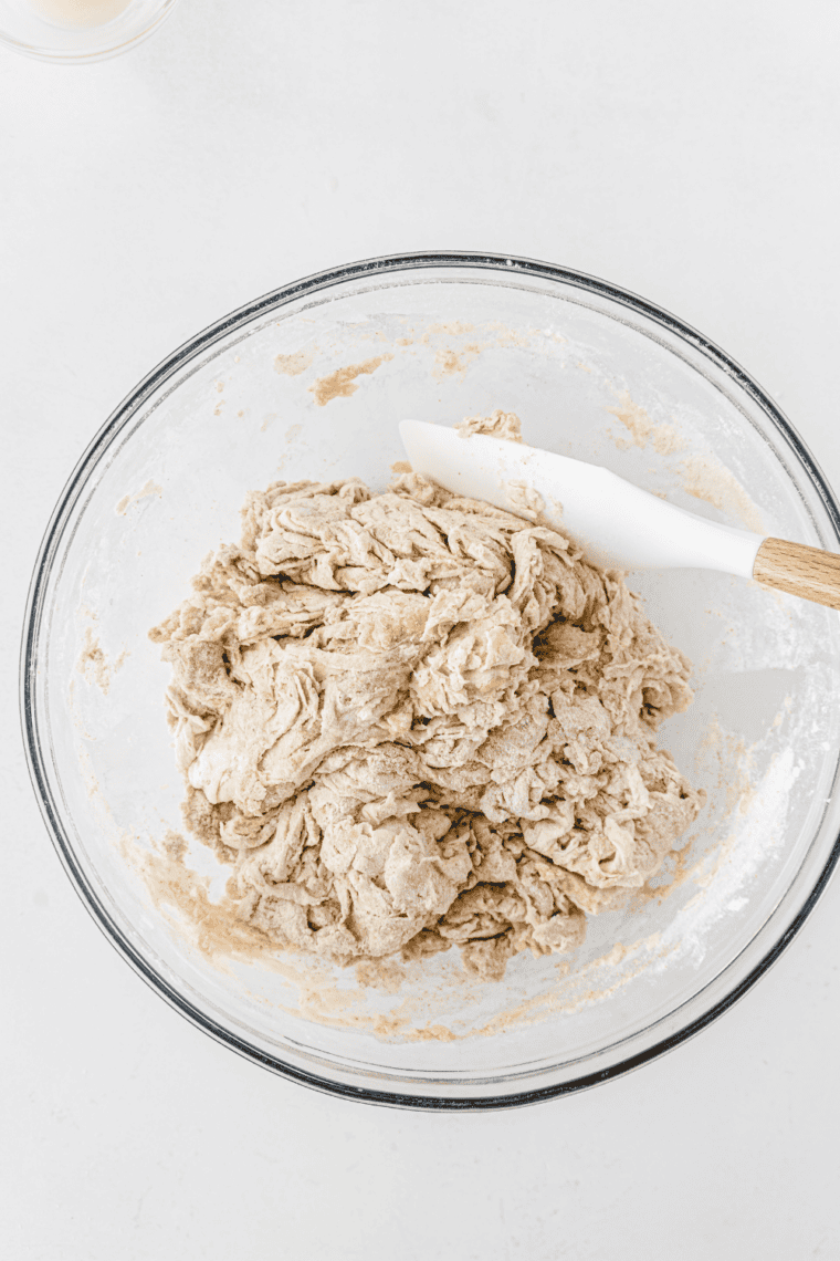 Mixing flour and salt with yeast mixture – Hands combining flour, salt, and foamy yeast mixture in a large bowl to form dough.