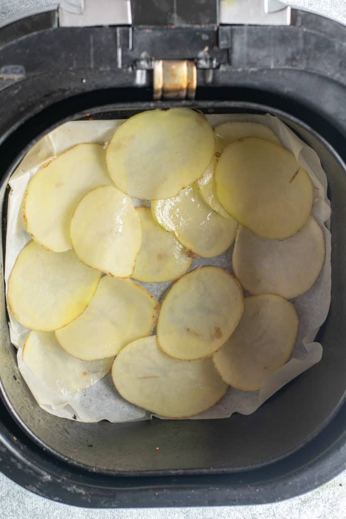 air fryer basket with raw potato slices