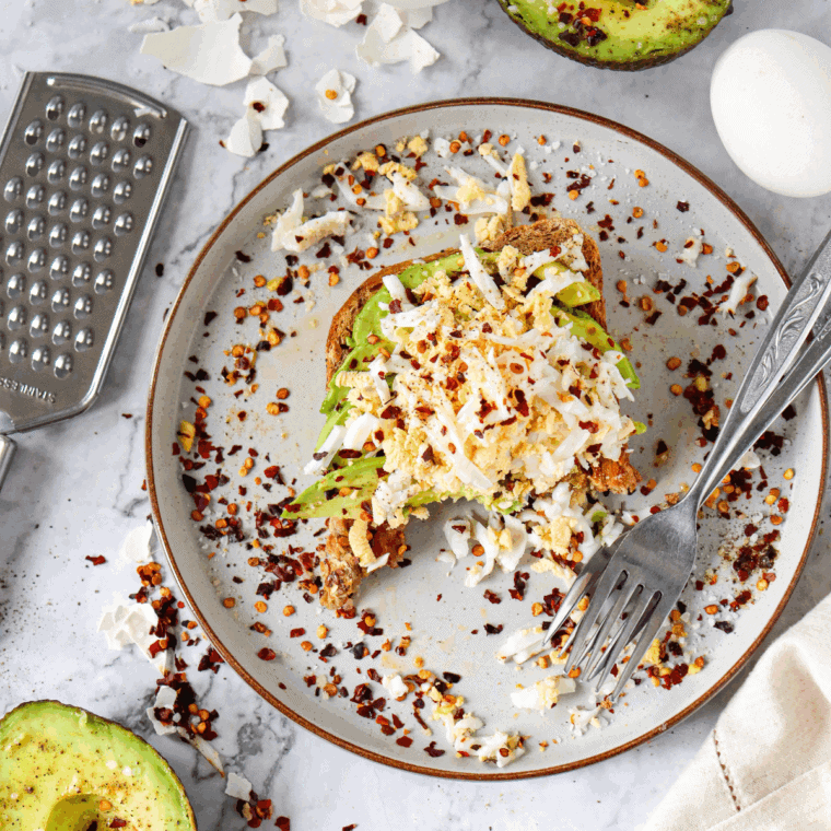 A plate of crispy Air Fryer Avocado Toast, topped with creamy avocado and garnished with seasonings.