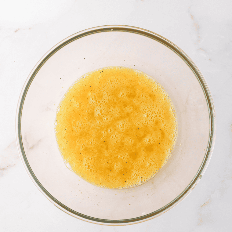 Whisking eggs, salt, pepper, and seasonings together in a bowl for stuffed peppers.