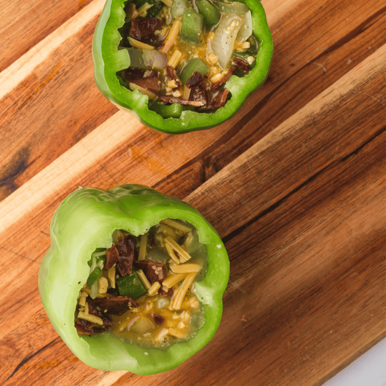 Pouring the egg mixture into hollowed bell peppers, filling them about ¾ of the way full.