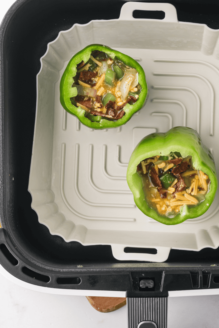 Placing stuffed peppers in the air fryer basket, set to 360°F (180°C), and cooking for 10-15 minutes until eggs are set and peppers are tender.