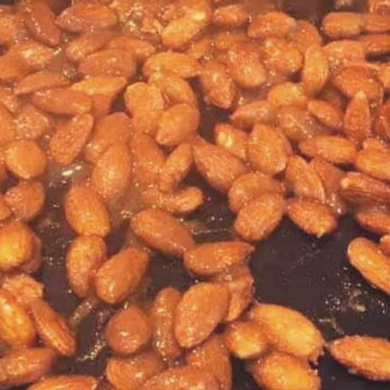 Coated almonds spread evenly in an air fryer basket, ready to cook at 300°F for 10–12 minutes