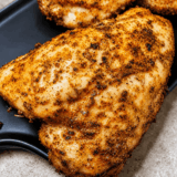 "Air Fryer Caribbean Rubbed Chicken Thighs on a white plate, crispy golden skin coated in smoky paprika spice rub"
