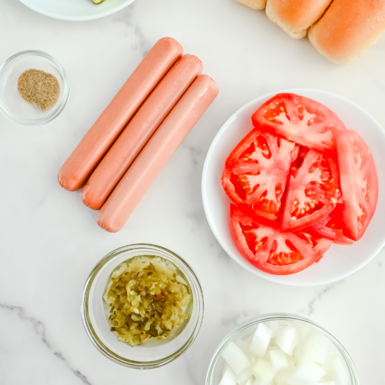 Ingredients for Air Fryer Chili Cheese Hot Dogs - An arrangement of hot dogs, chili, cheese, and buns on a wooden cutting board.