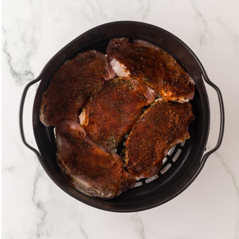 Pork chops in a single layer in the air fryer basket, flipped halfway through cooking
