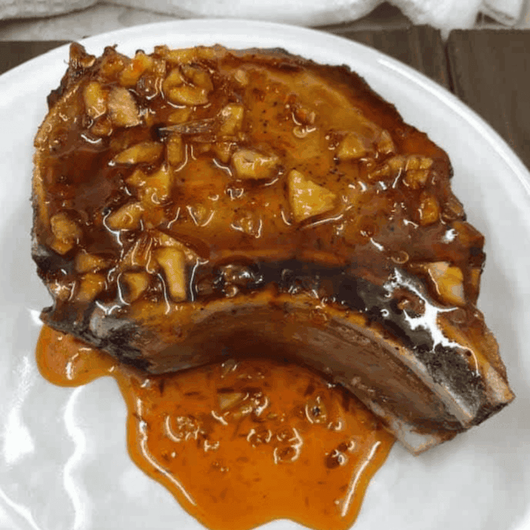 Air fryer honey garlic pork chops cooked golden brown, garnished and served with sides.