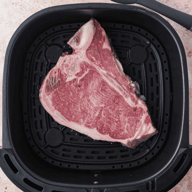Place raw T-Bone steak brushed with butter into the air fryer basket.