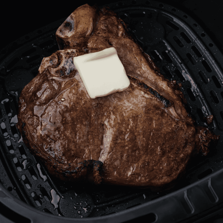 Air Fryer T Bone Steak cooked in the air fryer basket, with butter.