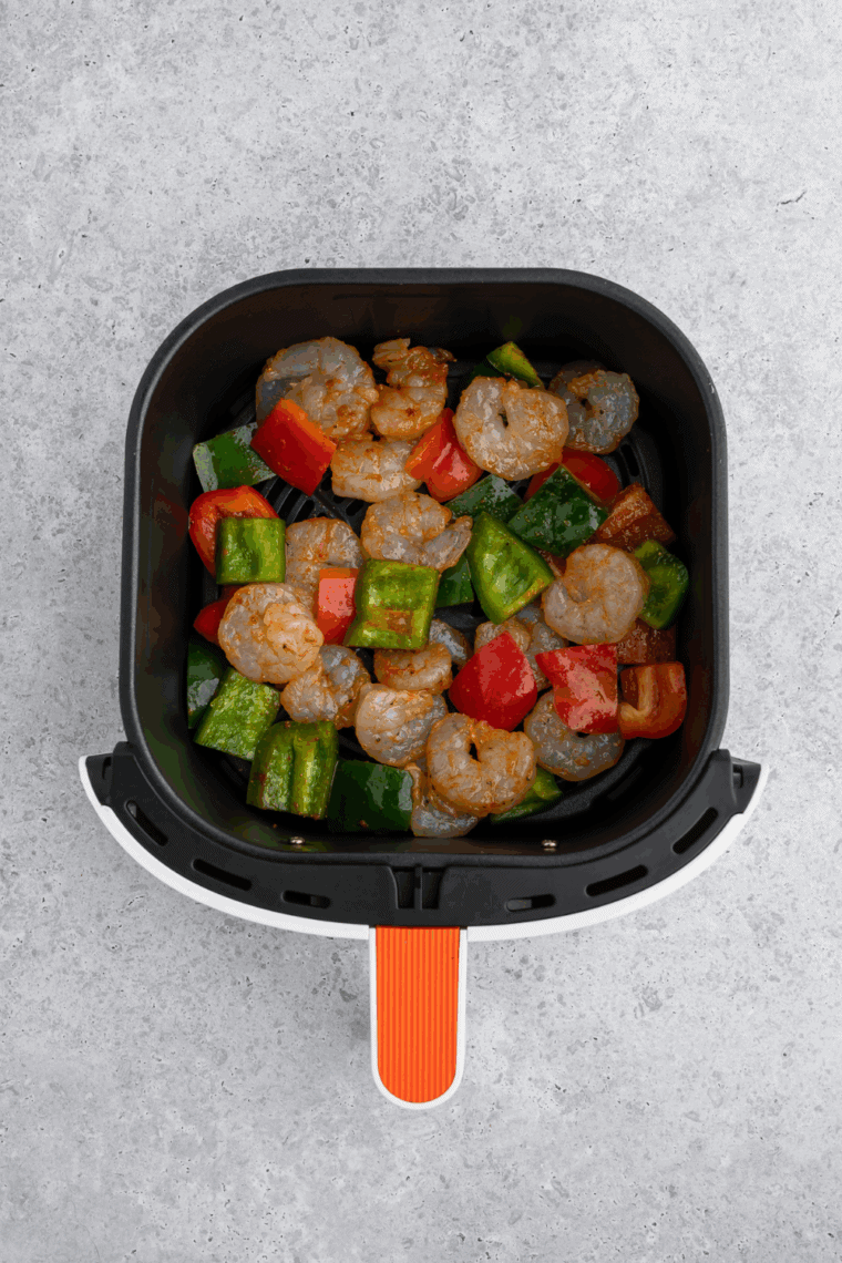 Sweet and sour shrimp cooking in air fryer, shaking halfway through