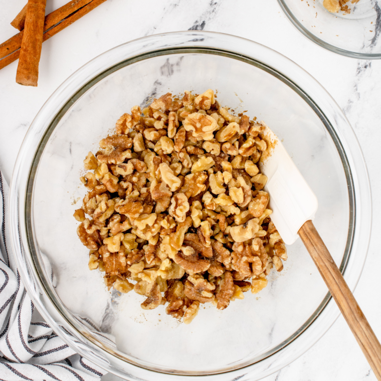 overhead: nuts in a large bowl with a spatula before roasting walnuts in air fryer