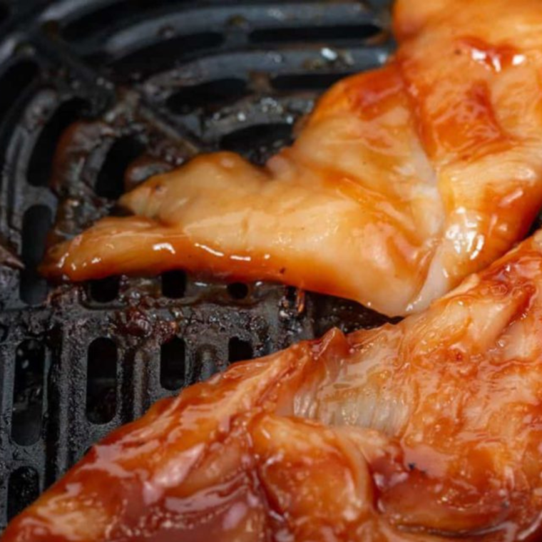 Marinated chicken tenders coated in bourbon BBQ sauce in a mixing bowl.