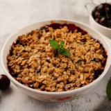 Air fryer cherry crisp in a small dish with golden oat topping and bubbling cherry filling