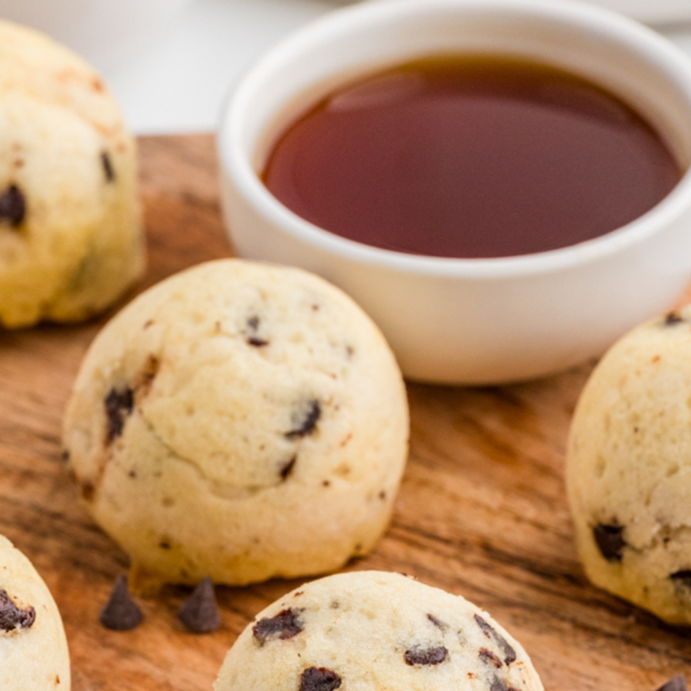 Deliciously fluffy Air Fryer Chocolate Chip Pancake Bites served on a plate, drizzled with maple syrup and topped with chocolate chips.