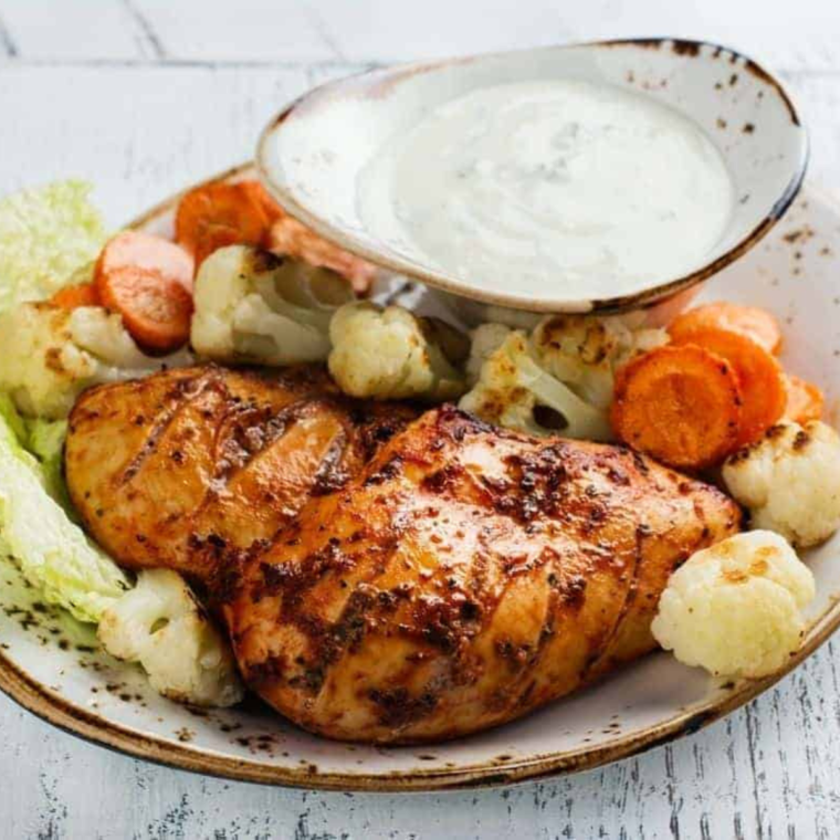 Grilled chicken tenders cooked in the air fryer, golden brown and juicy, served on a white plate with dipping sauce.