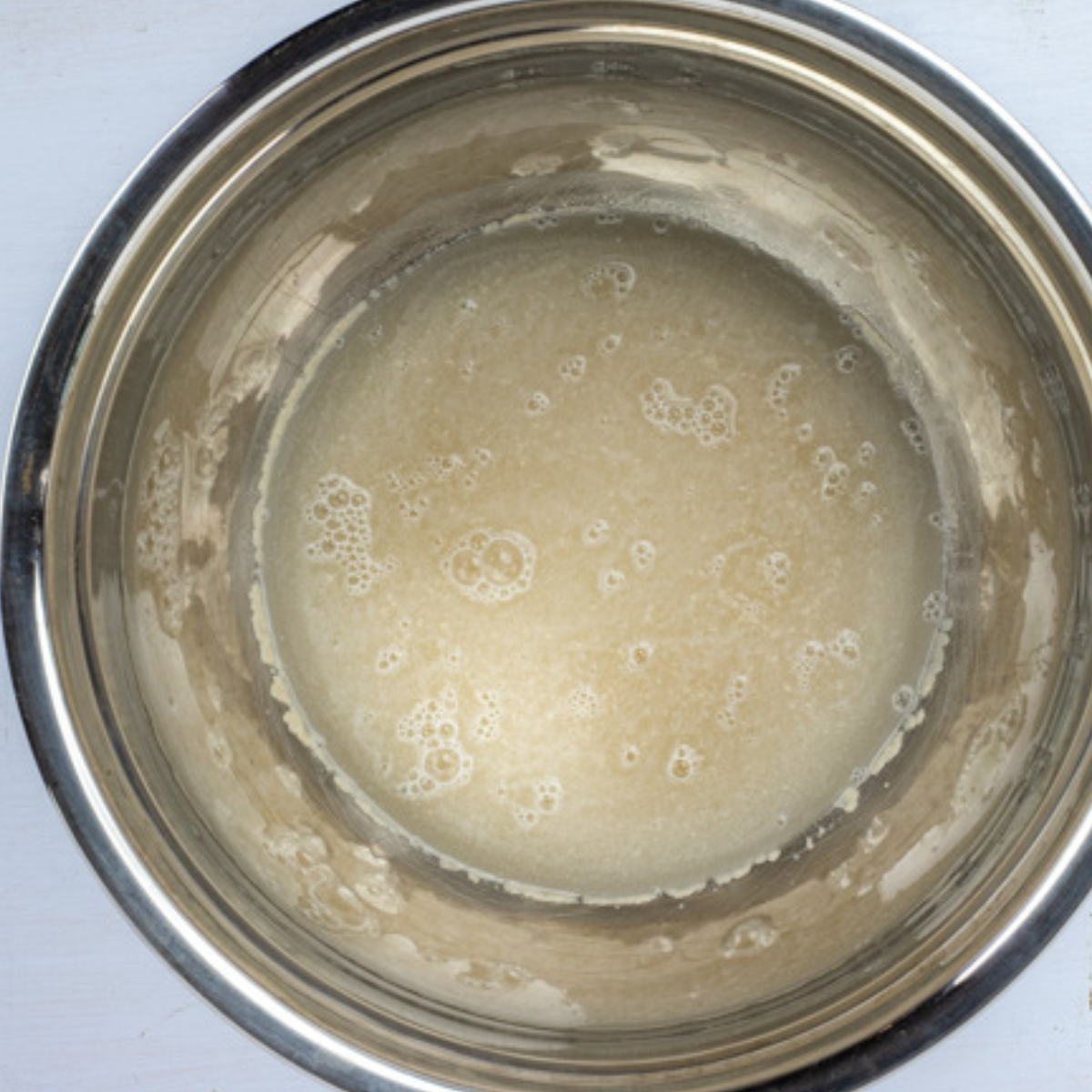 Mixing yeast, warm water, and sugar in a large bowl, waiting for the foam to form after 5 minutes.