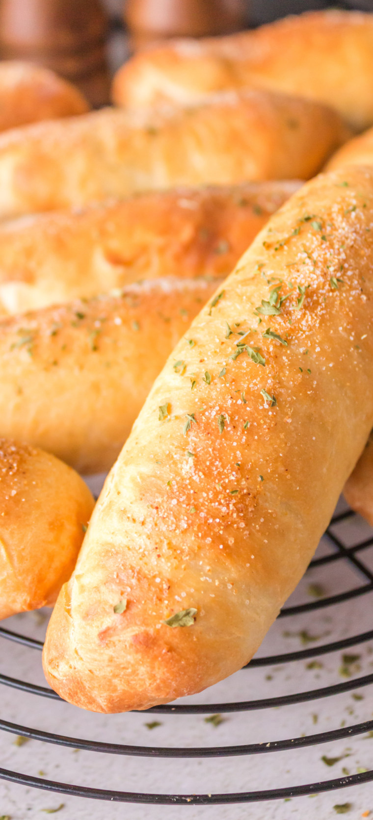 A plate of golden, fluffy, and buttery air fryer copycat Olive Garden breadsticks sprinkled with Italian seasoning, served with marinara sauce.