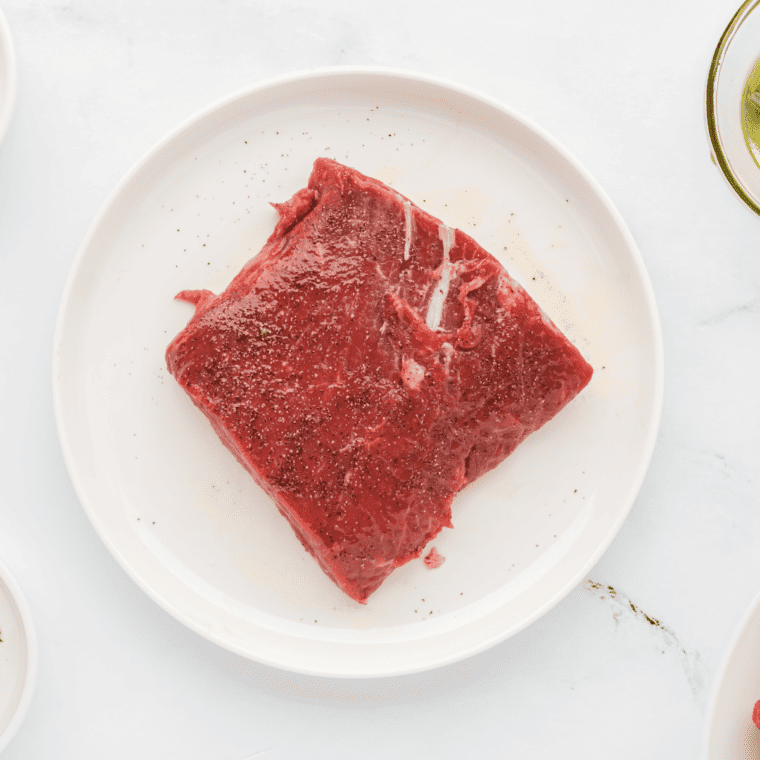 Seasoning flat iron steaks with olive oil, salt, and black pepper before air frying.