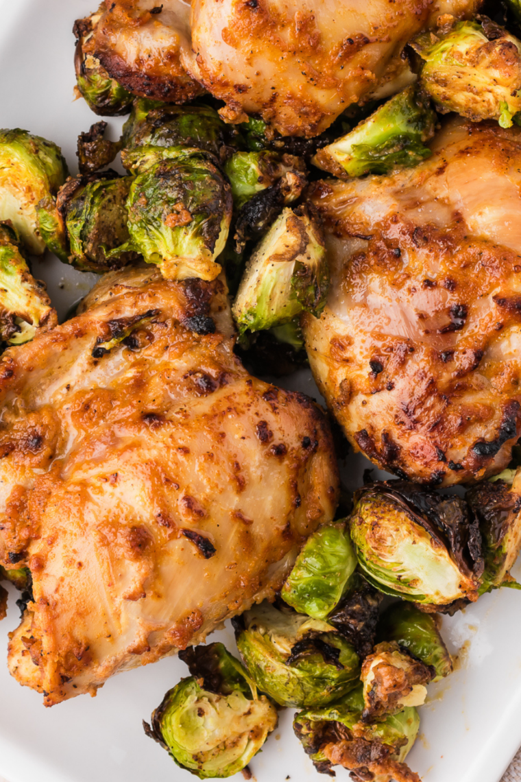 Air fryer honey balsamic Brussels sprouts with glossy glaze plated next to crispy chicken thighs