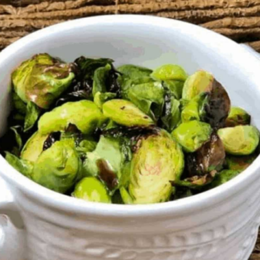 Crispy air fryer honey balsamic Brussels sprouts with caramelized edges tossed in a glossy dark glaze in a white serving bowl