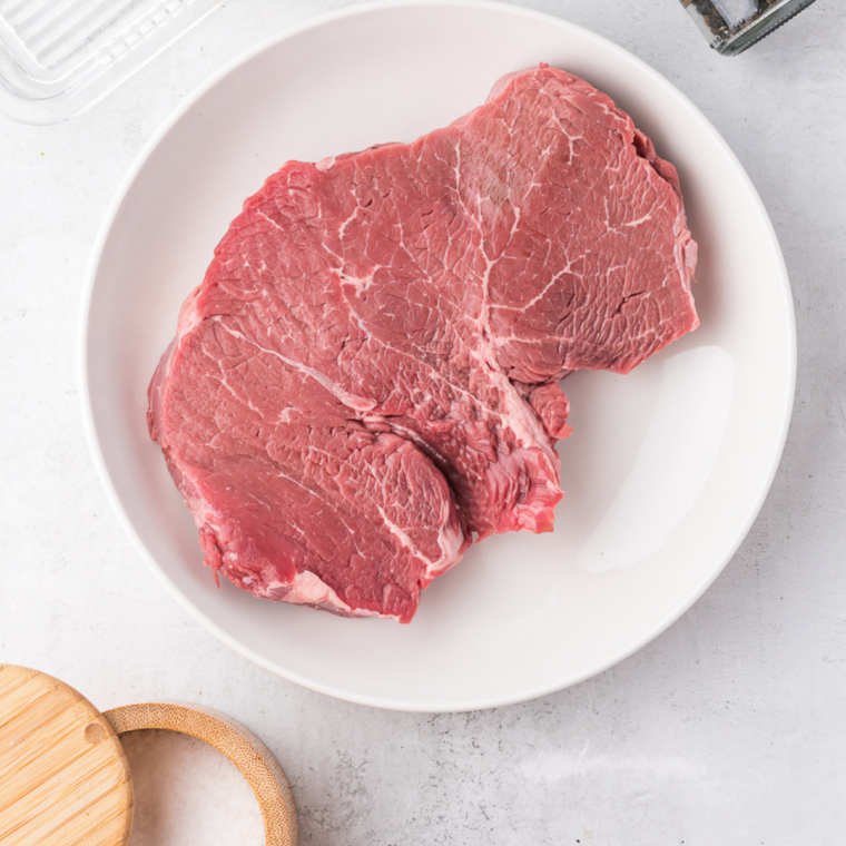 Steak removed from fridge and resting on counter to reach room temperature before cooking for even doneness