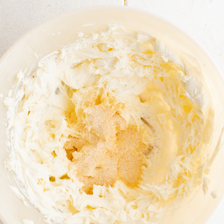 Homemade Boursin cheese mixture being mixed with cream cheese, butter, garlic, and fresh herbs in a bowl