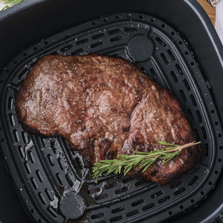 Juicy air fryer New York strip steak topped with melted Boursin cheese on a plate