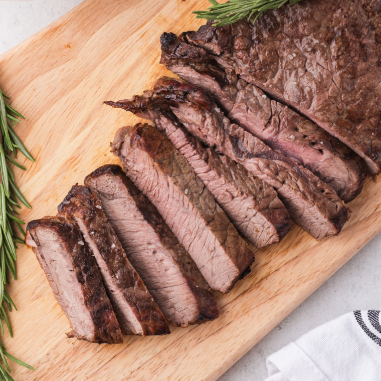 Sliced New York strip steak cooked in air fryer with creamy garlic herb cheese on top