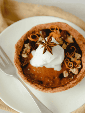 Air fryer pumpkin pie with a flaky crust and creamy spiced filling, topped with whipped cream