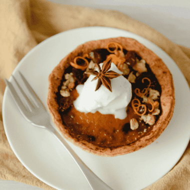 Air fryer pumpkin pie with a flaky crust and creamy spiced filling, topped with whipped cream