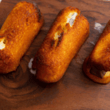 Golden, crispy air fryer Twinkies served on a plate with powdered sugar.