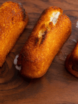 Golden, crispy air fryer Twinkies served on a plate with powdered sugar.